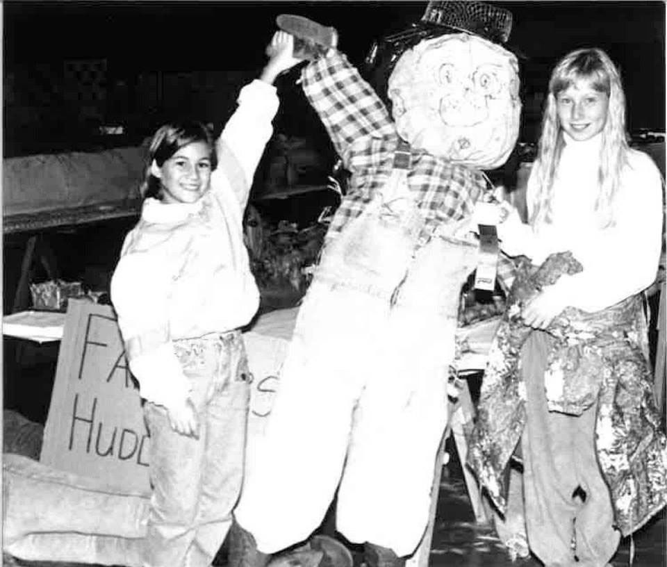 Girls posing with scarecrow