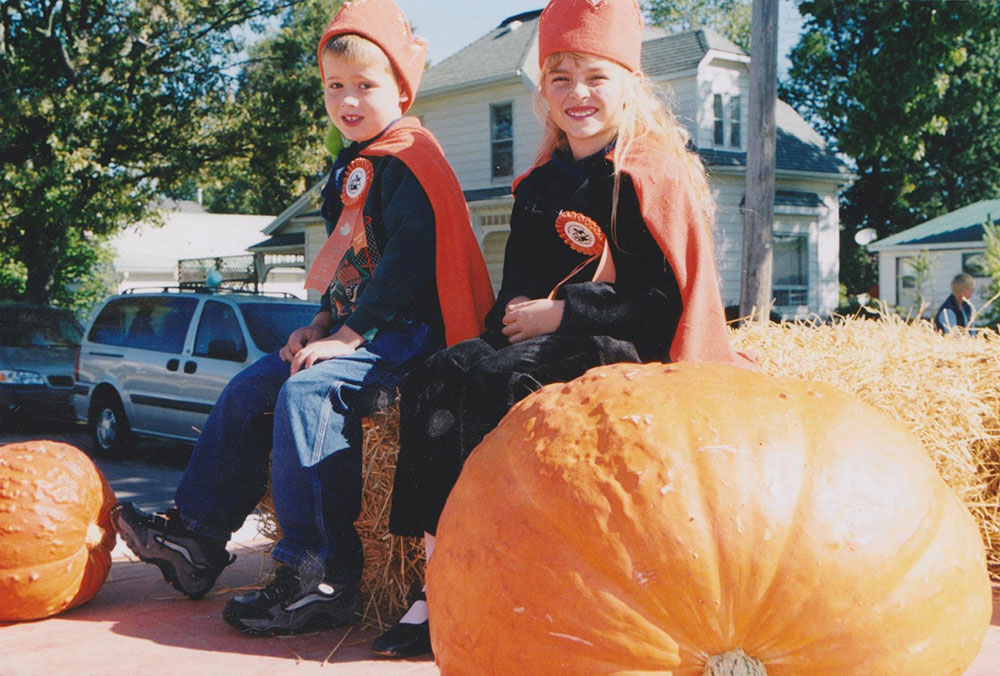 Kids sitting beside pumpkins